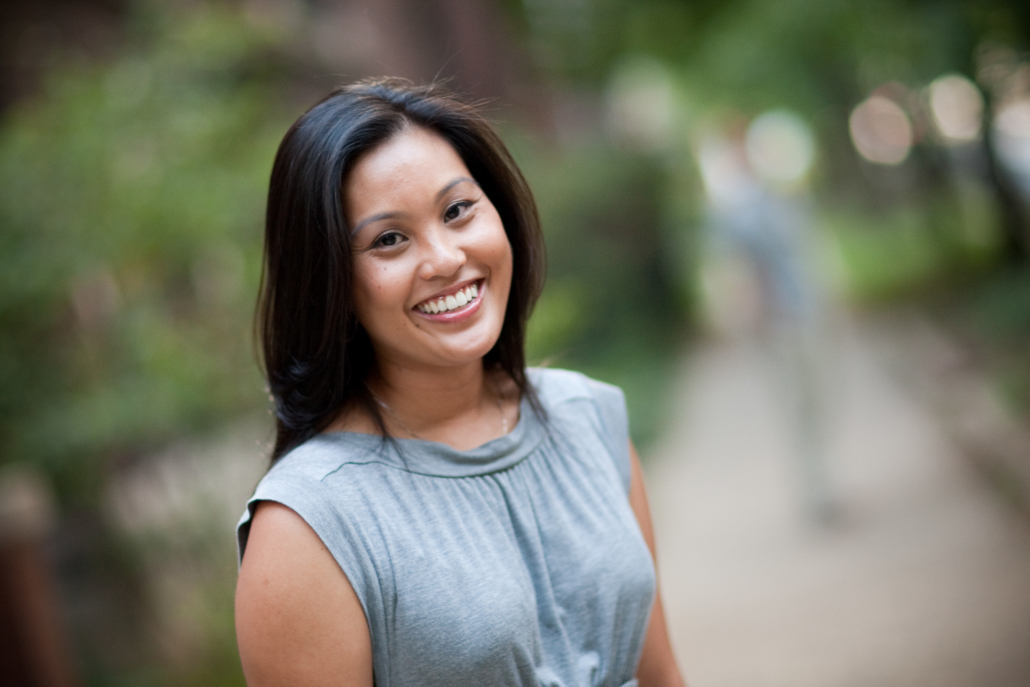 Dominique Enriquez smiling in a gray blouse against a blured background of greenery