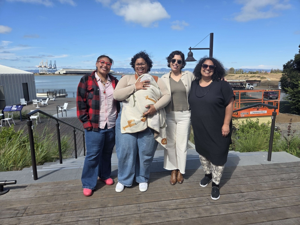 Photo of leadership: four adults and one baby standing together outside smiling