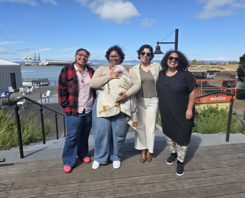Photo of leadership: four adults and one baby standing together outside smiling