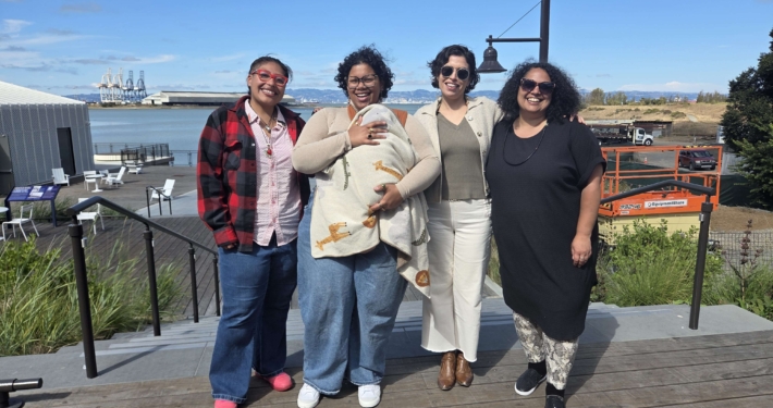 Photo of leadership: four adults and one baby standing together outside smiling